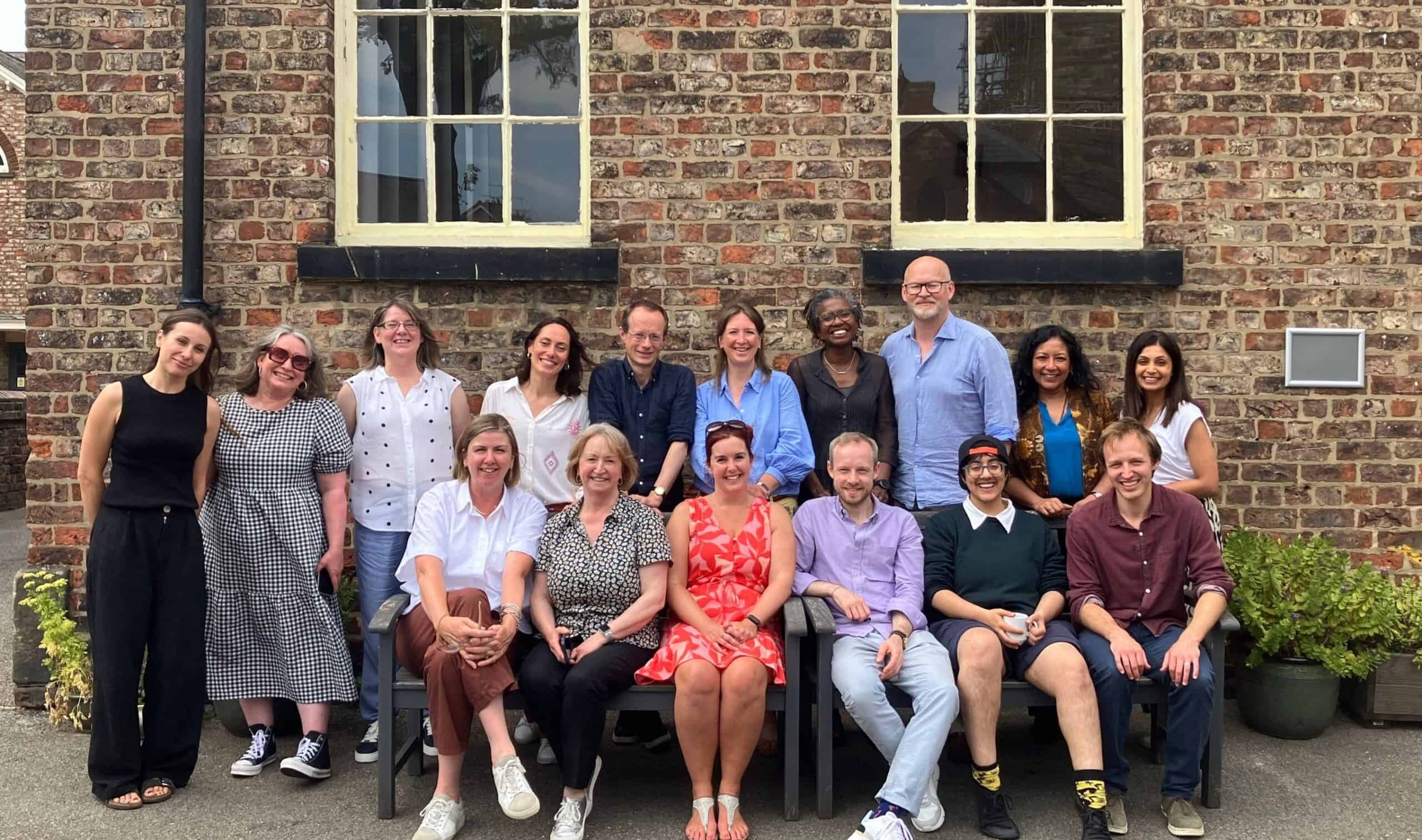 Friends Provident Foundation staff and trustees sat on and around a bench in the sunshine.