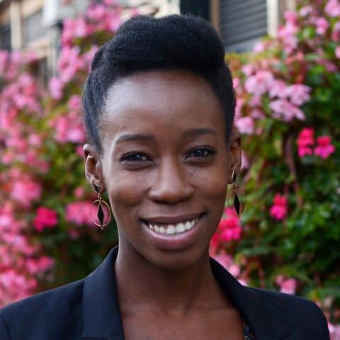 Headshot of Sayo Ayodele, smiling to camera against a floral background