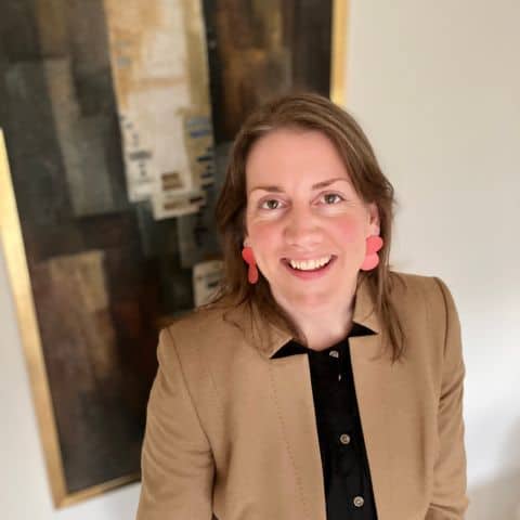 Sarah Heathwood, a white woman with brown hair, in front of an abstract artwork.