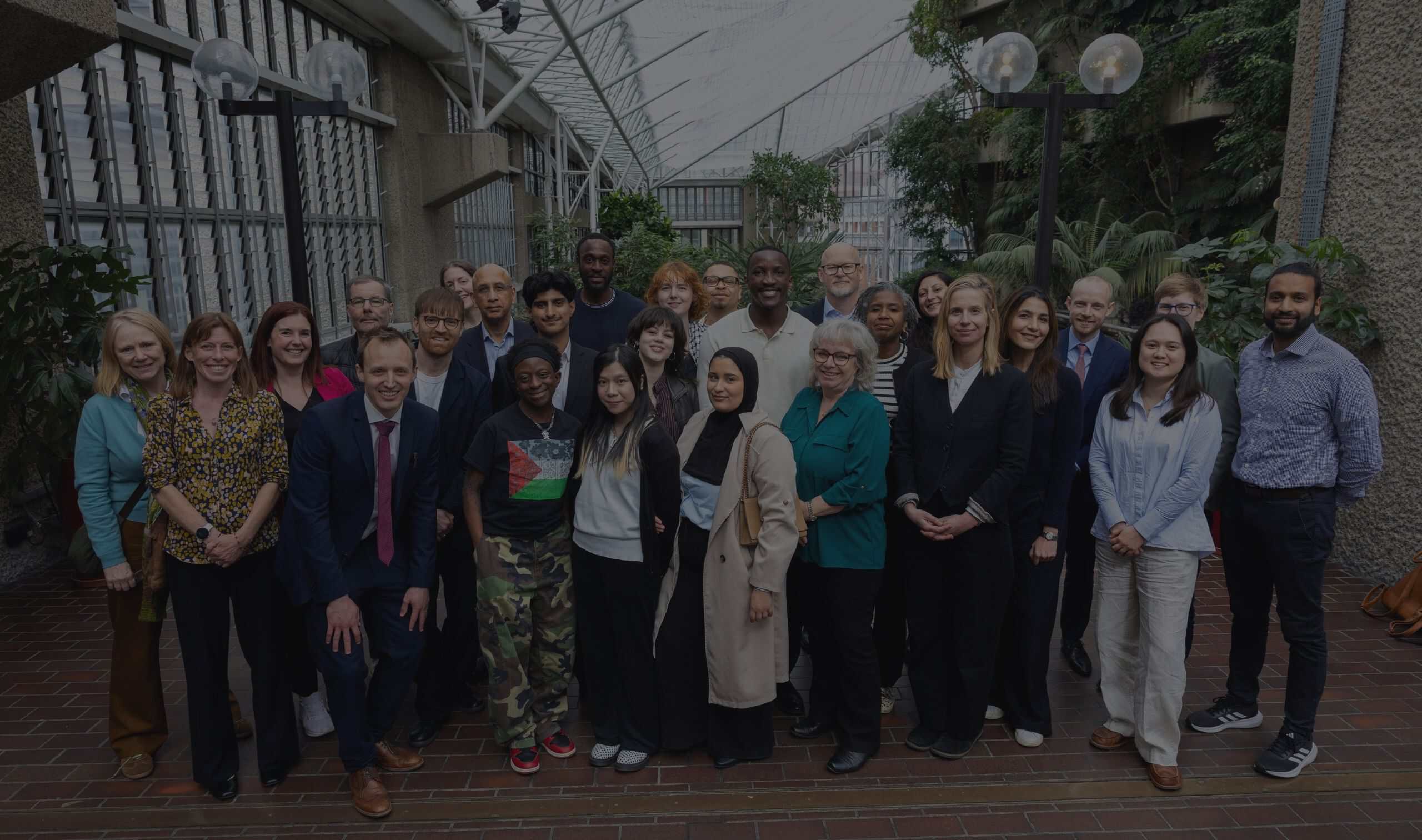 A diverse group of around 25 people stood together on a terrace.