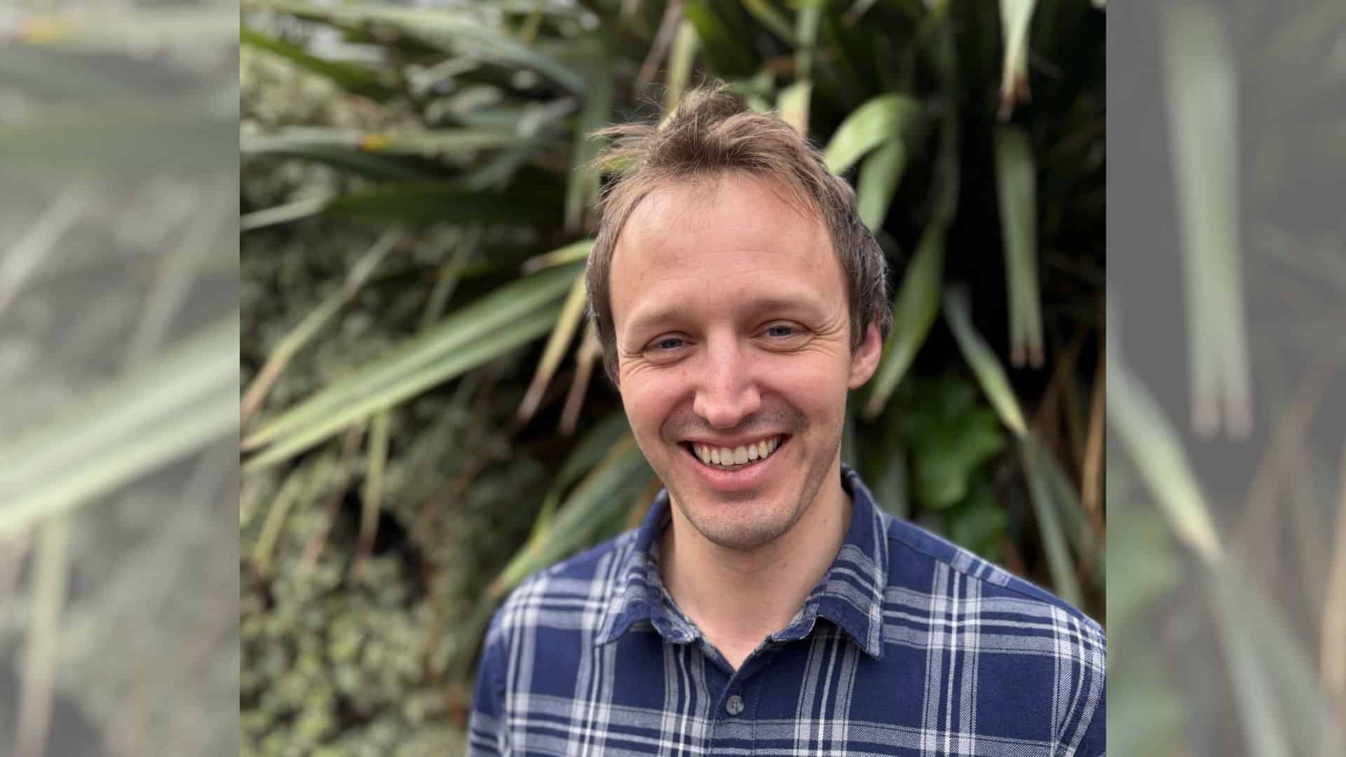 Charlie Crossley, investment engagement manager, smiling to camera in front of a green leafy background