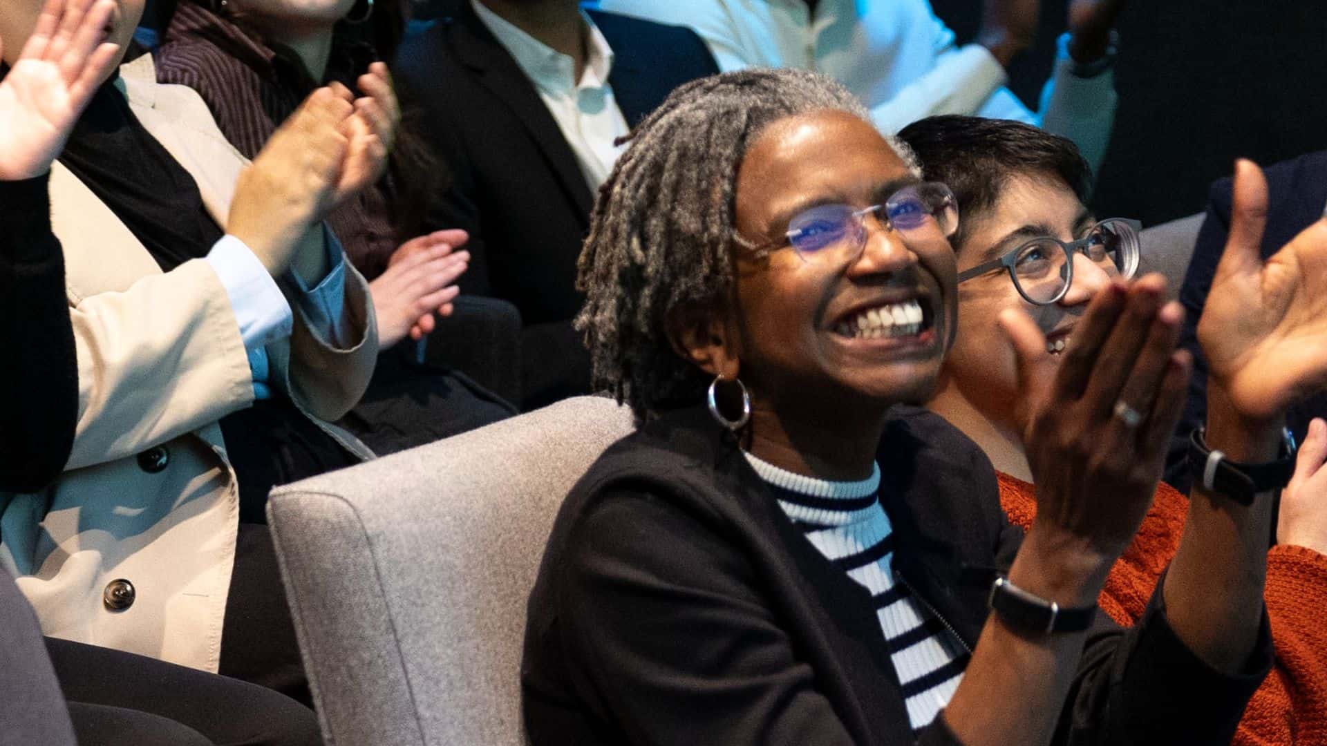 Danielle Walker Palmour looking toward a stage, smiling and applauding